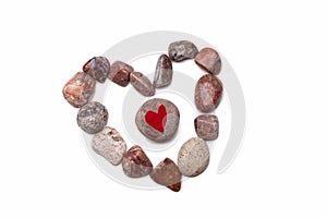 A heart of pebbles surrounds a pebble with a red heart