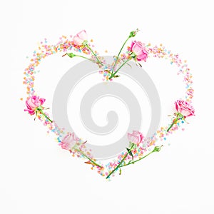 Heart with pink flowers and candy confetti on white background. Flat lay, Top view. Valentine`s day composition