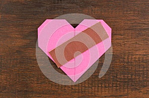 Heart with plaster on wooden background