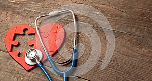 Heart puzzle red and stethoscope on wooden background. Concept diagnosis and treatment of heart disease, medical insurance