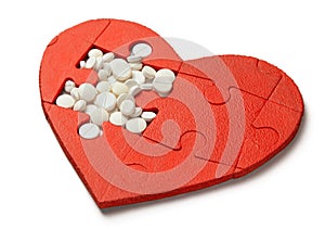Heart puzzle red and white pills isolated on white background. Concept treatment of heart disease pills