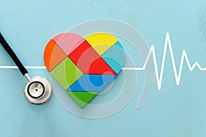 Heart puzzle and with stethoscope on blue pastel wooden background, medical concept