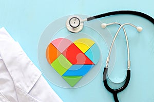 Heart puzzle and with stethoscope on blue pastel wooden background, medical concept