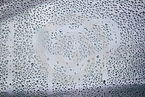 Heart and raindrops. Drawn romantic blurred love symbol drawn by hand on the wet window glass, light background