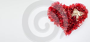 Heart of red Christmas tinsel with a decorative golden bow. Isolated on white.