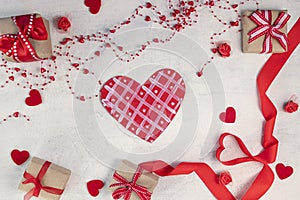 Heart from a red ribbon, gifts with a red ribbon and red hearts on a white stone background. Valentine`s day background. Valentin