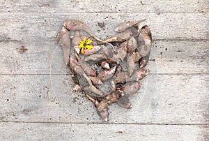 Heart from the roots of fresh organic topinambur or jerusalem artichoke Helianthus tuberosus on wooden background. Diabetic friend