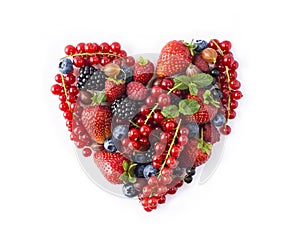 Heart shape assorted berry fruits on white background. Berries in heart shape isolated on a white. Ripe blueberries, red currants,