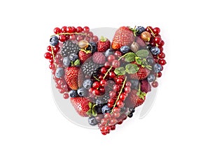 Heart shape assorted berry fruits on white background. Berries in heart shape isolated on a white. Ripe blueberries, red currants,