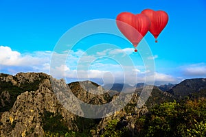 Heart shape ballooning flying over mountain photo