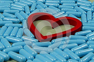 heart shape and blue capsules. Importance of medication treatment