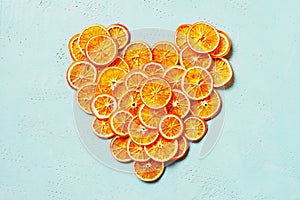 Heart shape of bright dry orange slices on the blue table