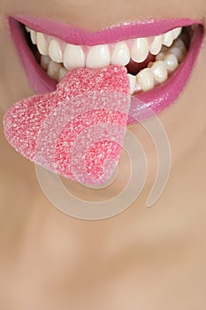 Heart shape candy on woman macro mouth