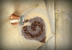 Heart shape with coffee beans and traditional Turkish copper coffee pot on a burlap