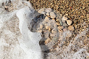 Heart shape created with sea pebbles on a sand and waves