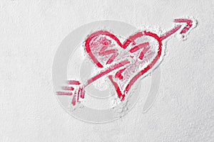 Heart shape with cupid arrow in flour on red board. Love sign