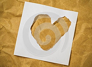 Heart shape in cut out magazine letters put on brown paper.