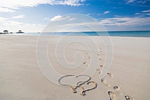 Heart shape drawing in the sand on tropical beach, romantic and honeymoon concept background for couples