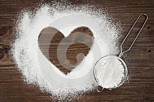 Heart shape of flour on brown wooden board background