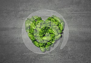 Heart shape from green hop cones on gray rustic stone background. Concept of organic beer production. Symbol of loving natural