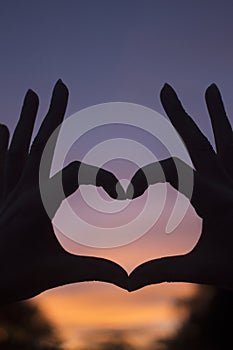 Heart shape hands at dusk silhouette sunset sky