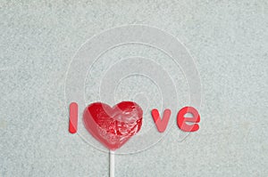 A heart shape lollipop replacing the letter o in the word love