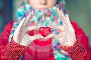 Heart shape love symbol in woman hands with face on background