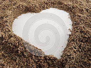 Heart shape made with beach sand on a white background