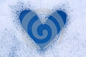 Heart shape made of detergent foam in water, top view. Hand washing laundry