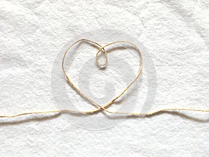 Heart shape made from hemp rope on softness cotton white background.