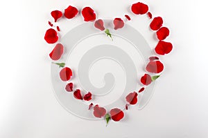 Heart shape made of red rose petals, on white background. Top view, copy space