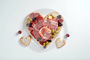 Heart shape made of traditional Spanish tapas, ham, salami, cheese and olives with bread. Flat lay with assorted appetizers for