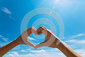 Heart shape making of hands against blue sky Hands Woman