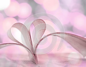 Heart shape from opened book pages with bokeh background.