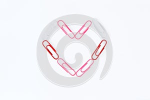 Heart shape by paper clips on white background