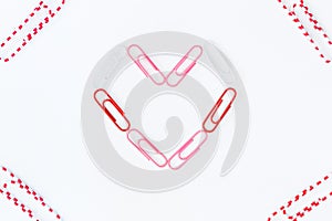 Heart shape by paper clips on white background