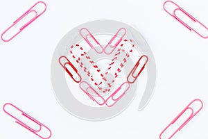 Heart shape by paper clips on white background