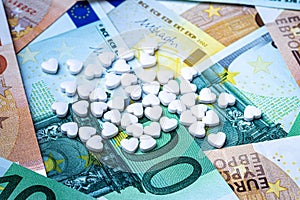 Heart-shape pills on the background of euro bills