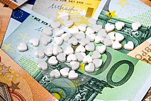 Heart-shape pills on the background of euro bills