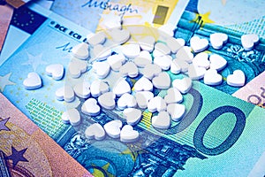 Heart-shape pills on the background of euro bills. The concept of the expensive cost of healthcare