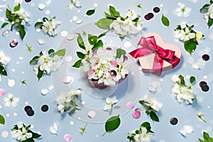 Heart shape pink present box, white flowers on blue background. 14 february love still life with garland light