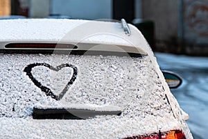 Heart shape on snow covered car rear window