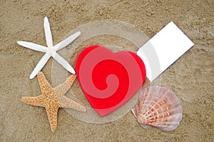 Heart shape, starfishes, seashell and paper on the beach