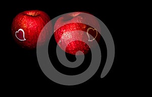 Heart shape sticker and water droplet on glossy surface of red apple on black background