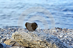 Heart shape stone against background of beach. Summer sunny day. Love, wedding and Valentine day concept. Finding