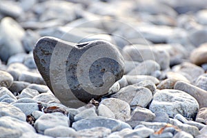 Heart shape stone against background of beach. Summer sunny day. Love, wedding and Valentine day concept. Finding