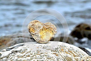 Heart shape stone against background of beach. Summer sunny day. Love, wedding and Valentine day concept. Finding