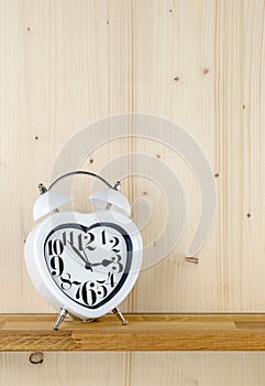 A heart shaped alarm clock on a shelf