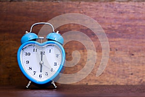 Heart shaped alarm clock on wooden background. Six O Clock
