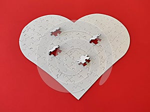 Heart shaped blank white jigsaw puzzle on red background puzzle pieces completing the heart shape
